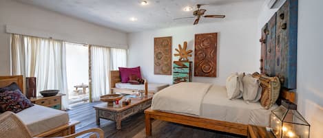 A spacious bedroom with a large bed, a wooden bench, and a wicker chair.