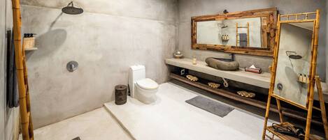 Un baño moderno con cabina de ducha, inodoro, lavabo con tocador y un espejo grande.