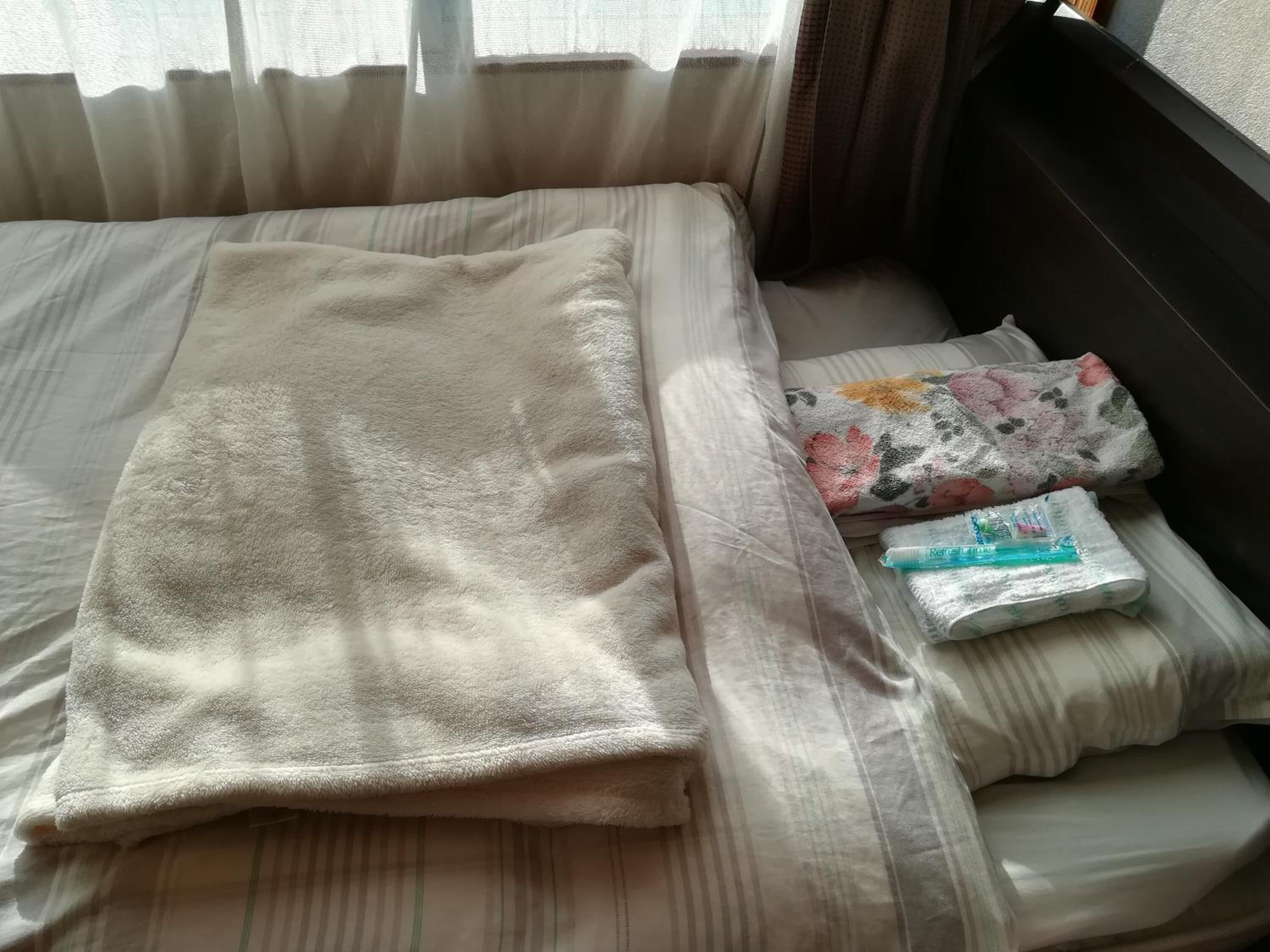 Ein Bett mit einer zusammengefalteten Decke und einem blumigen Kopfkissen.
