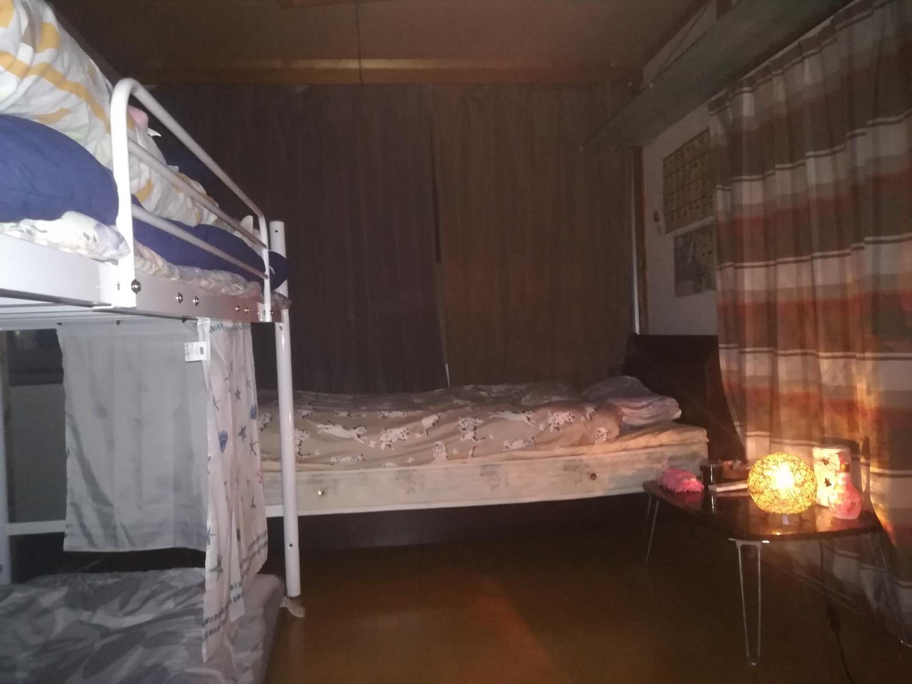 Una camera del dormitorio con letti a castello, una parete in legno, una tenda a quadri e un tavolo con una lampada.
