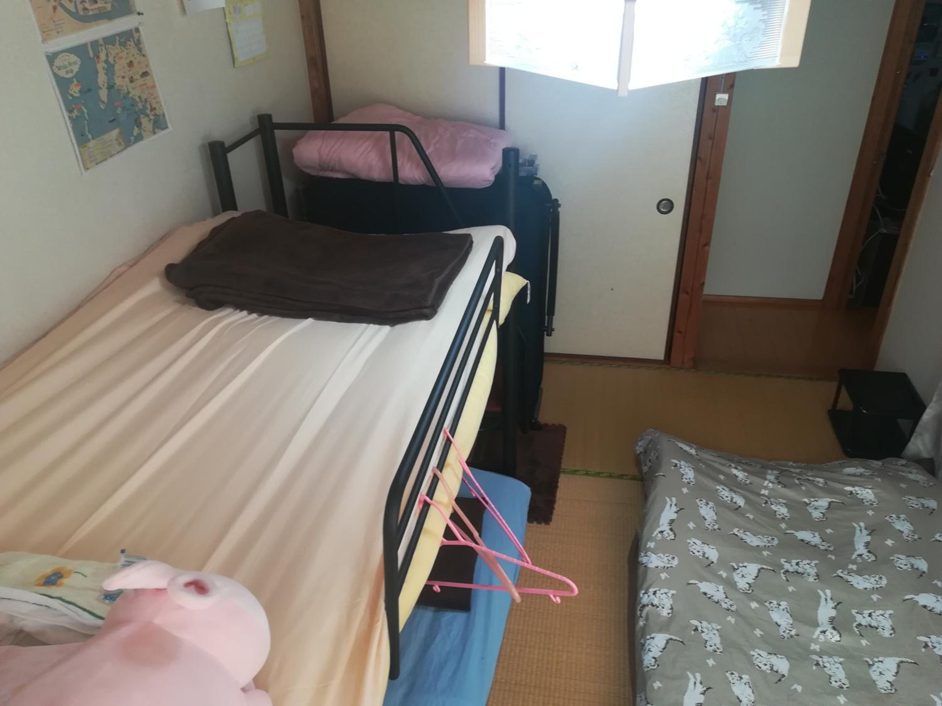 A dormitory room with bunk beds, a small desk, and a window.