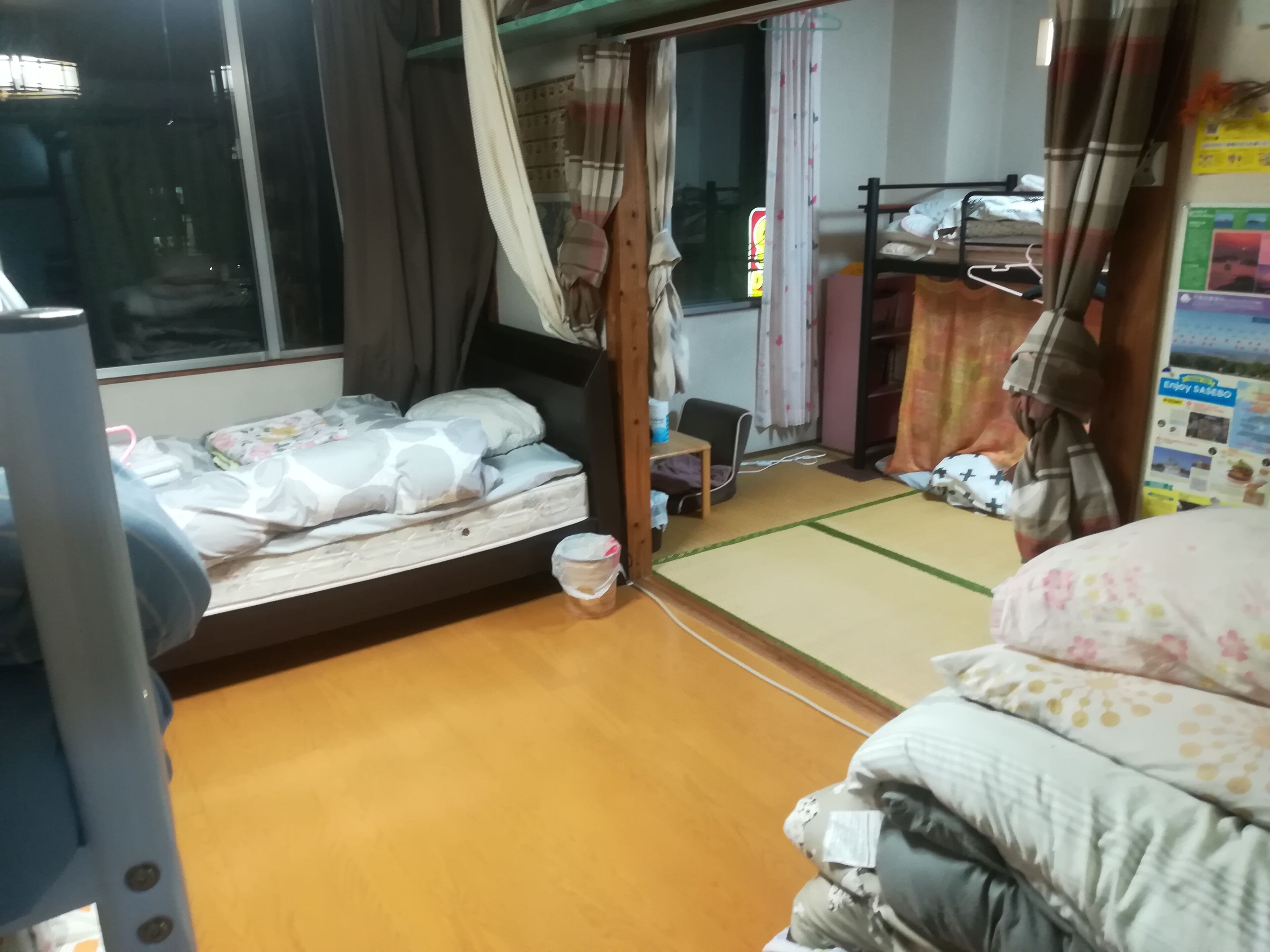 A hotel room with a bed, a small table, a chair, and a futon bed.