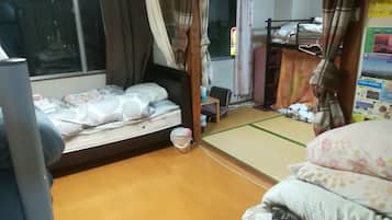 A hotel room with a bed, a small table, a chair, and a futon bed.