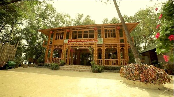Un bâtiment en bois, agrémenté d’une enseigne, entouré d’arbres et bordé d’une zone pavée.