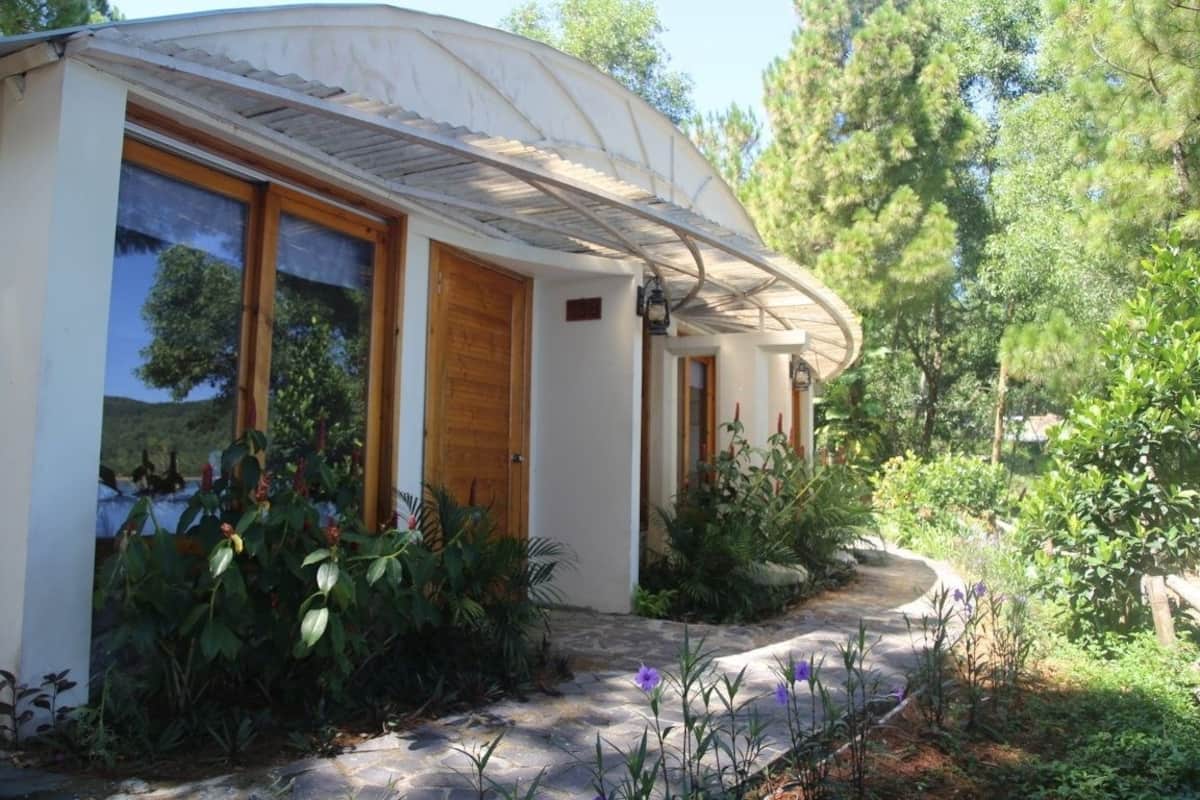 A small, single-story building with a curved roof, large windows, and a stone pathway leading to the entrance.