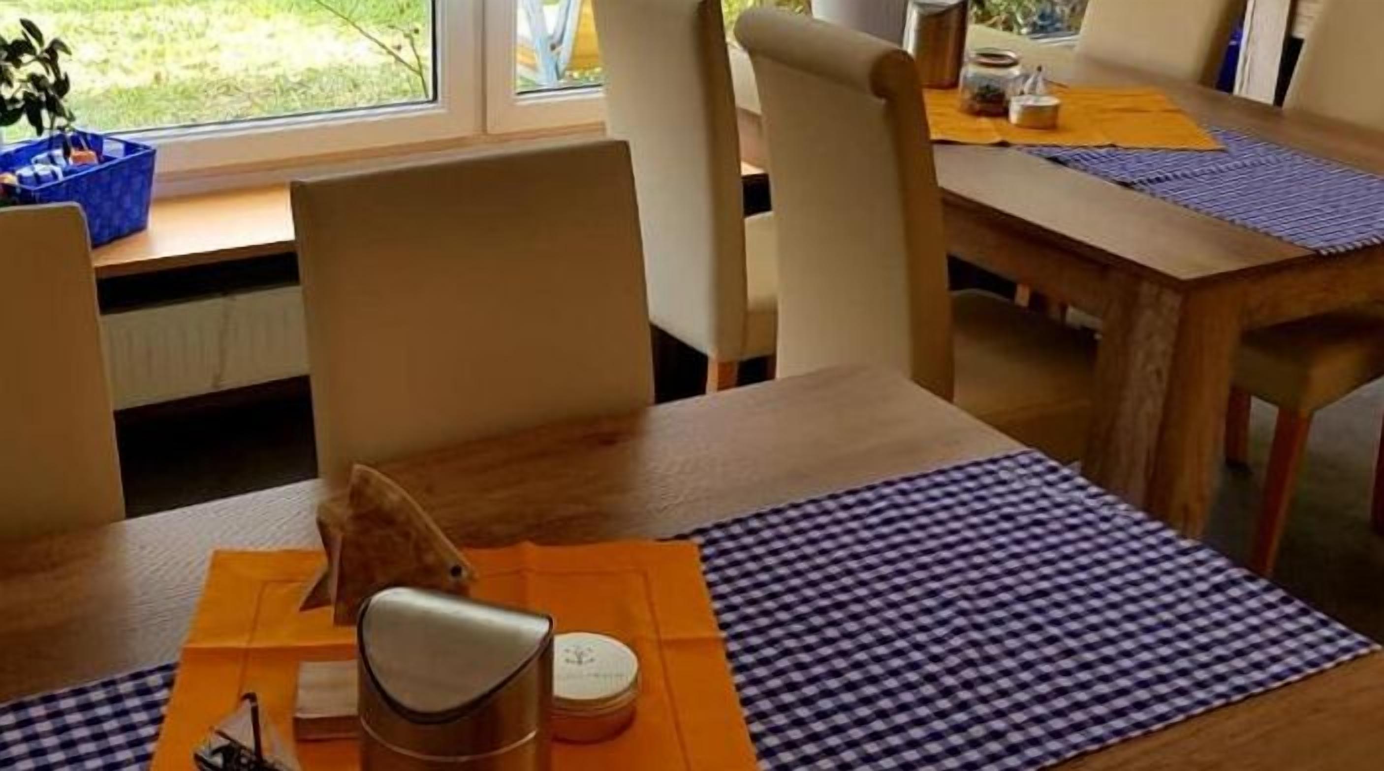 A dining area with a wooden table, chairs, and a view of the outdoors through a window.