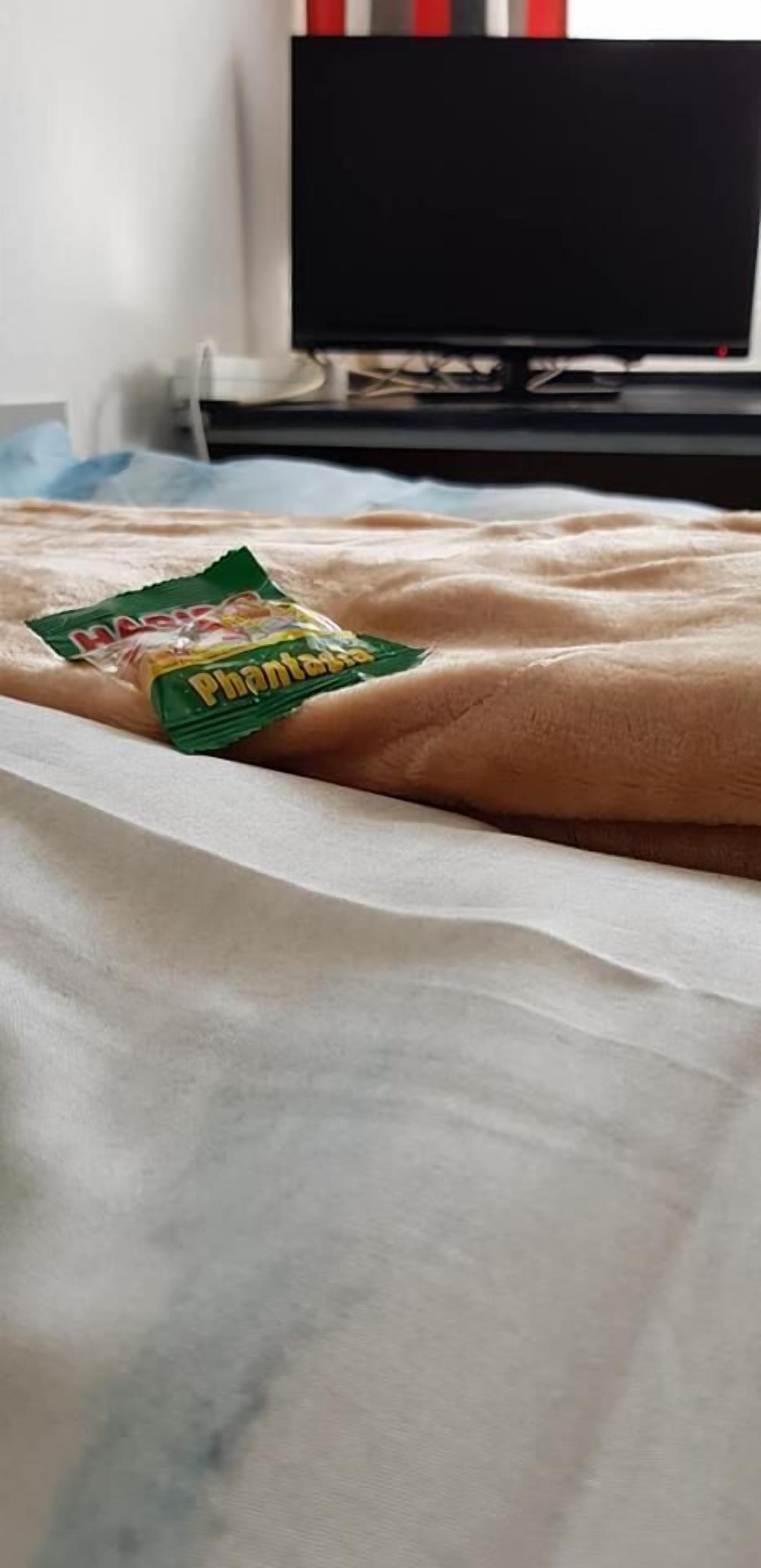 A bed with a green packet of Phantasia snacks on it.