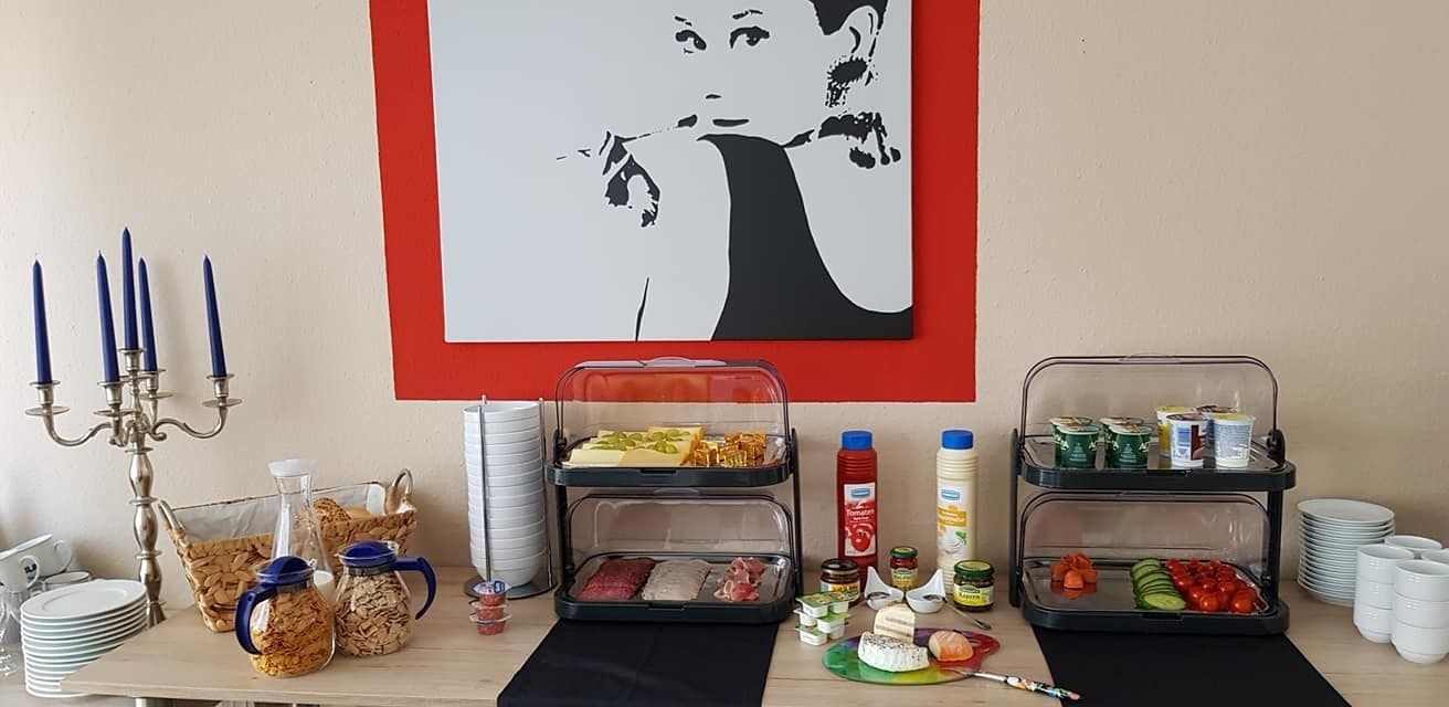 Montaje de un bufé de desayuno con diversos alimentos, como cereales, carnes y verduras, sobre una mesa con camino de mesa negro.