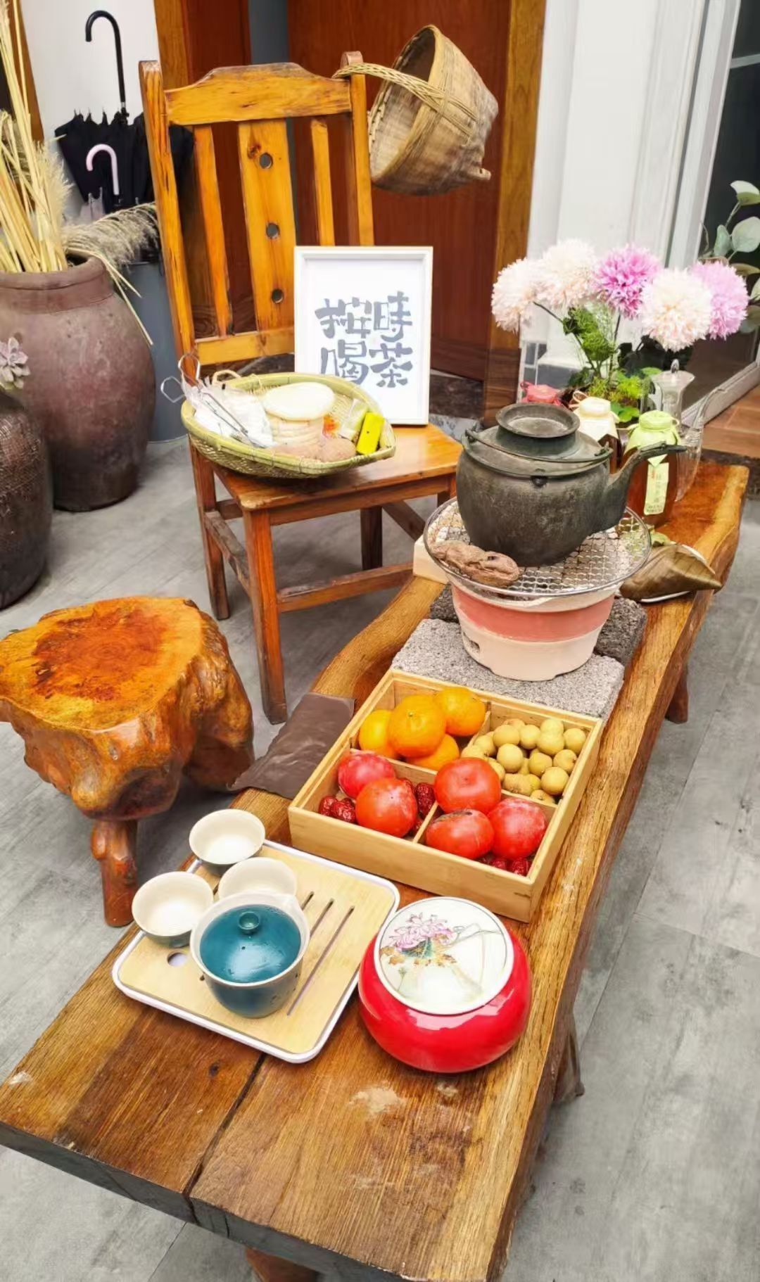 Una mesa de madera con un juego de té japonés tradicional, que incluye una tetera, tazas y una bandeja con frutas.