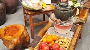 Una mesa de madera con un juego de té japonés tradicional, que incluye una tetera, tazas y una bandeja con frutas.