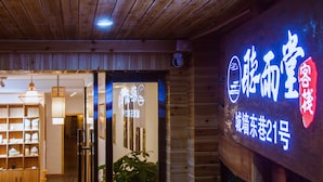 Interior de madera con un letrero de neón, estantes con objetos y una puerta.
