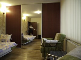 Una habitación de hotel con una cama, un sillón verde, una mesita y un espejo.