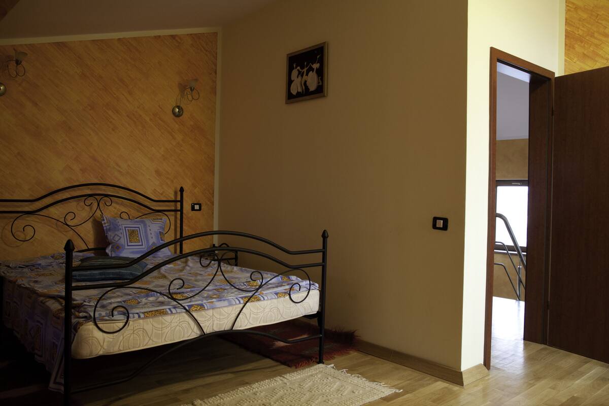 A bedroom with a bed, wooden walls, a door, and a small picture on the wall.
