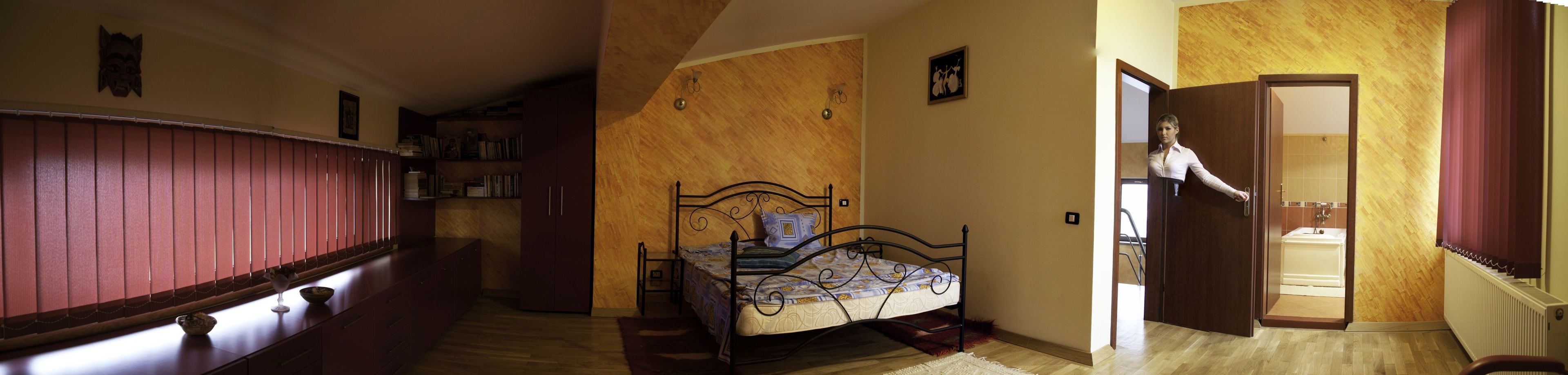 Een slaapkamer met een bed, een houten garderobe en een badkamer die door een open deur zichtbaar is.
