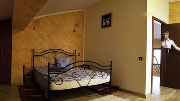 Een slaapkamer met een bed, een houten garderobe en een badkamer die door een open deur zichtbaar is.
