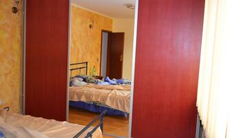 Una habitación con una cama, un espejo y suelo de madera.