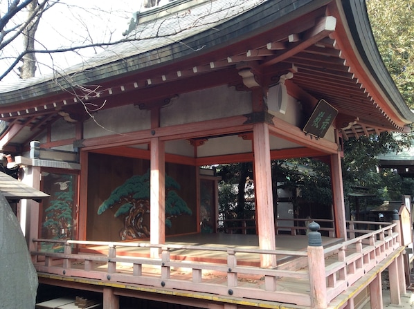 A traditional Japanese building with a wooden structure, a tiled roof, and a painted mural on the wall.