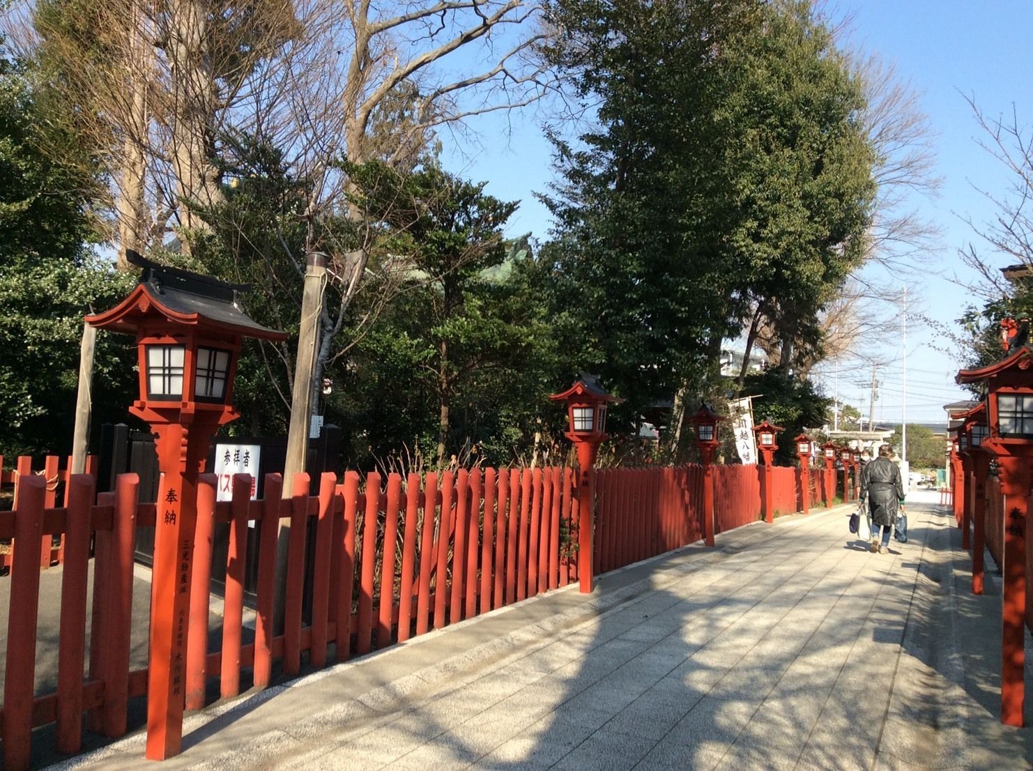Un torii tradicional japonés con faroles rojos y estructuras de madera, que da paso a un sendero.