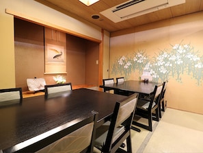 A conference room with a long table and chairs, a ceiling vent, and a wall with a floral mural.