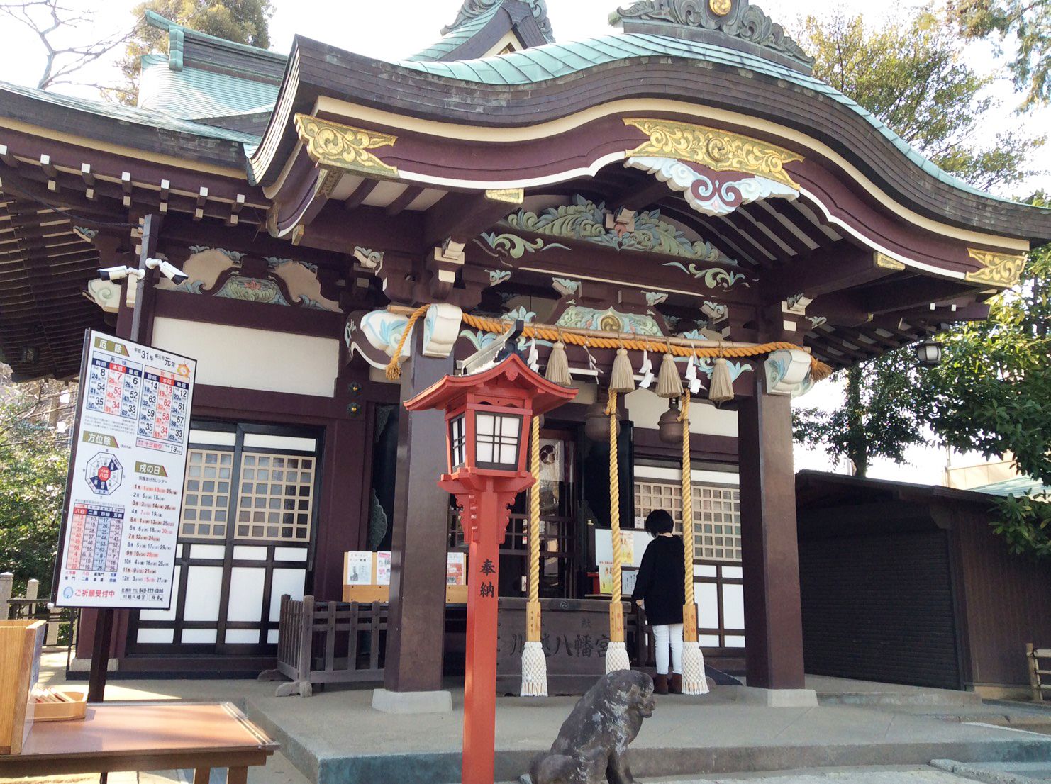 A traditional Japanese building with a curved roof, a red lantern, and a wooden fence.