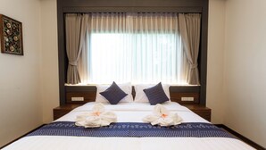 A hotel room with a large bed, two pillows, a window with curtains, and a wall-mounted artwork. - Lima Lanna Hotel (Chiang Mai)