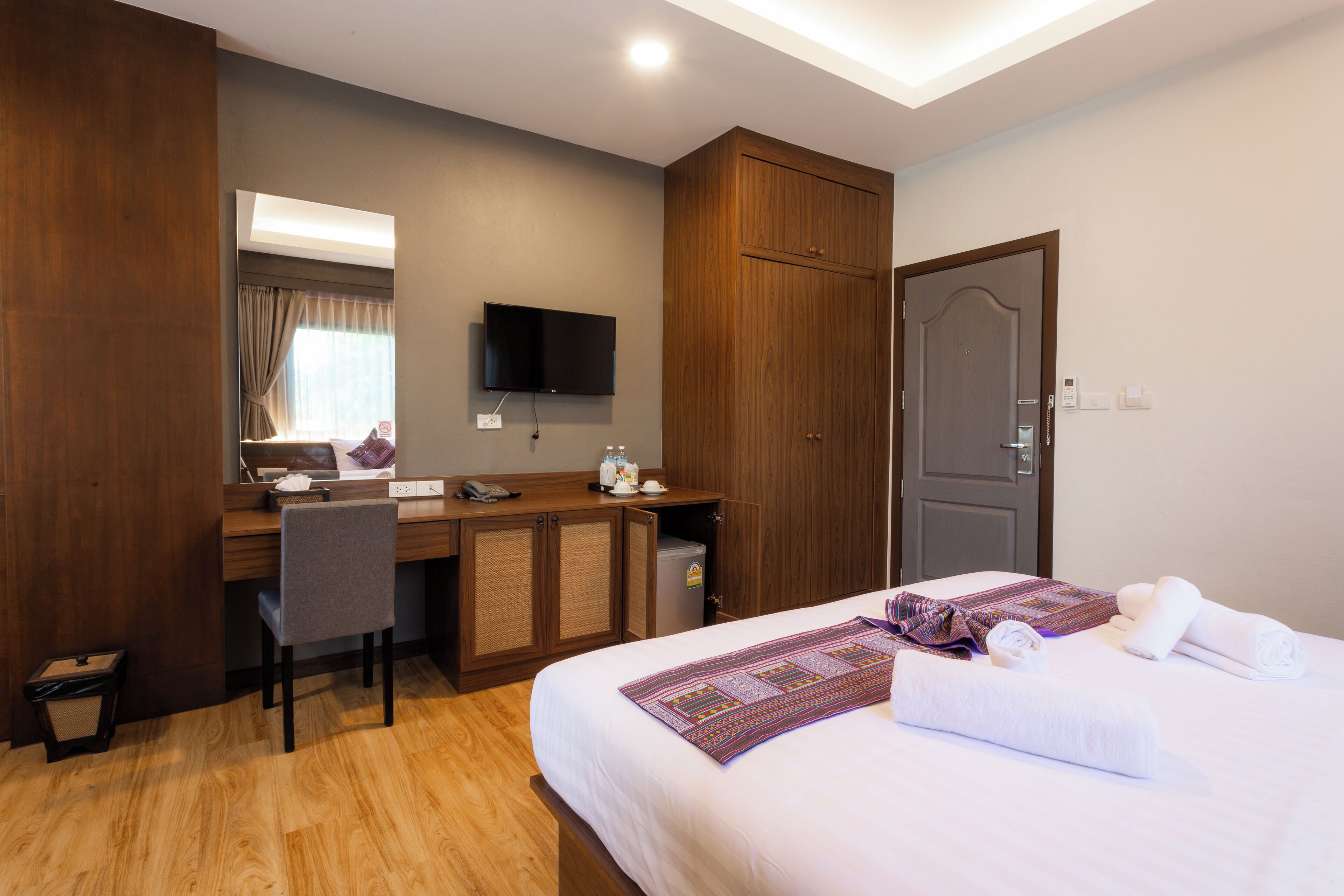 A hotel room with a bed, a desk, a chair, a television, and a wardrobe.