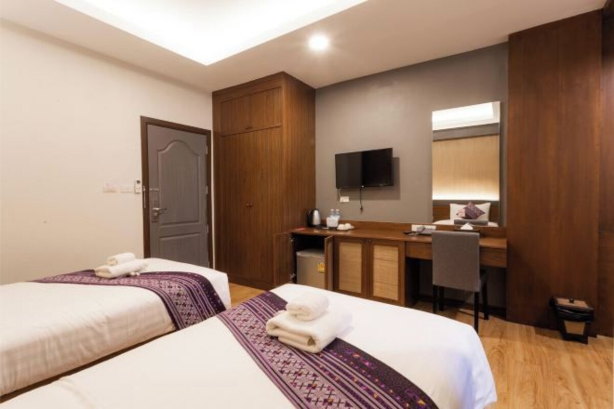 Ein Hotelzimmer mit zwei Betten, einem Schreibtisch, einem Stuhl, einem Fernseher und einem Kleiderschrank.
