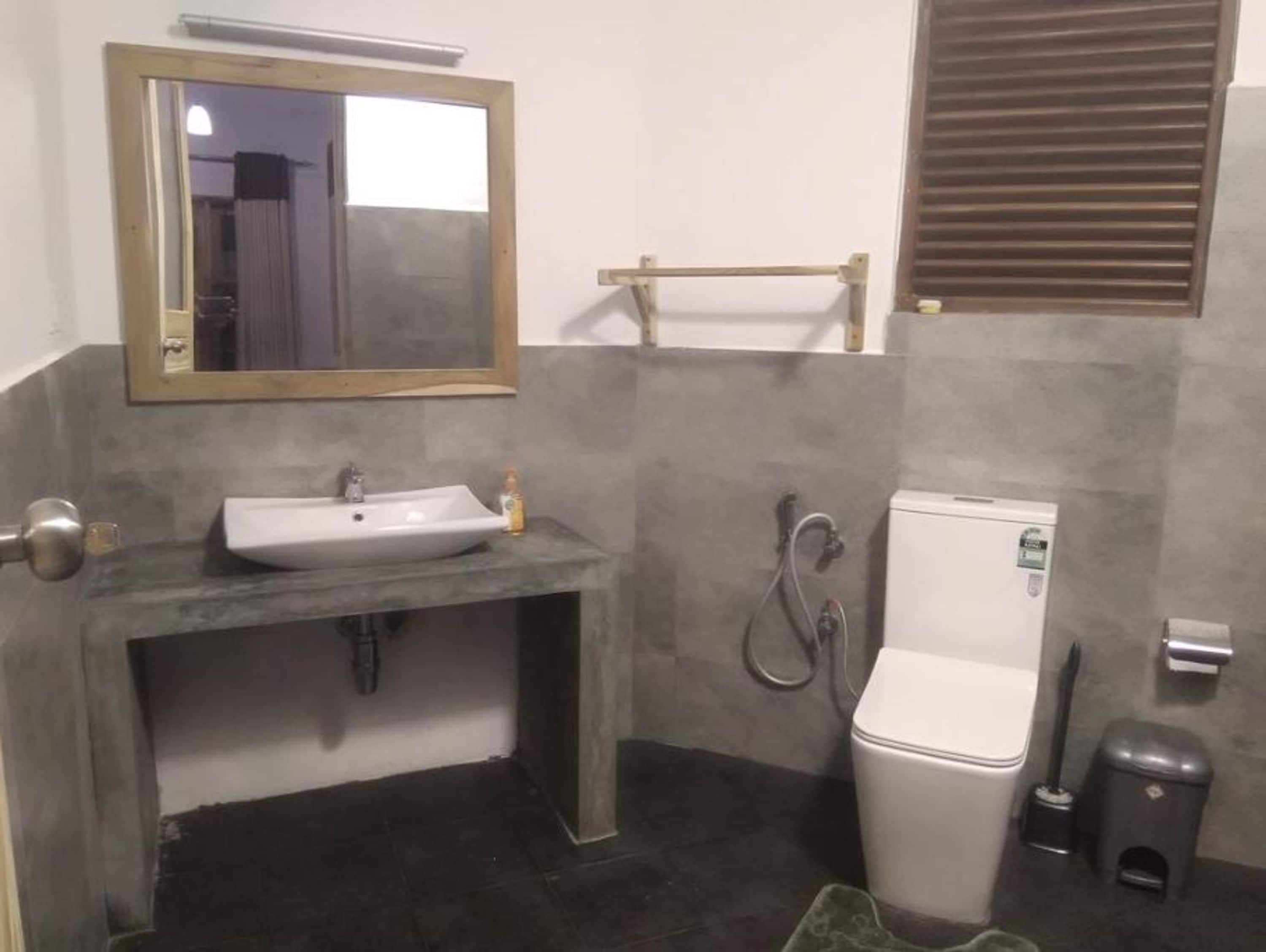 Un bagno con lavandino, specchio e water bianchi.