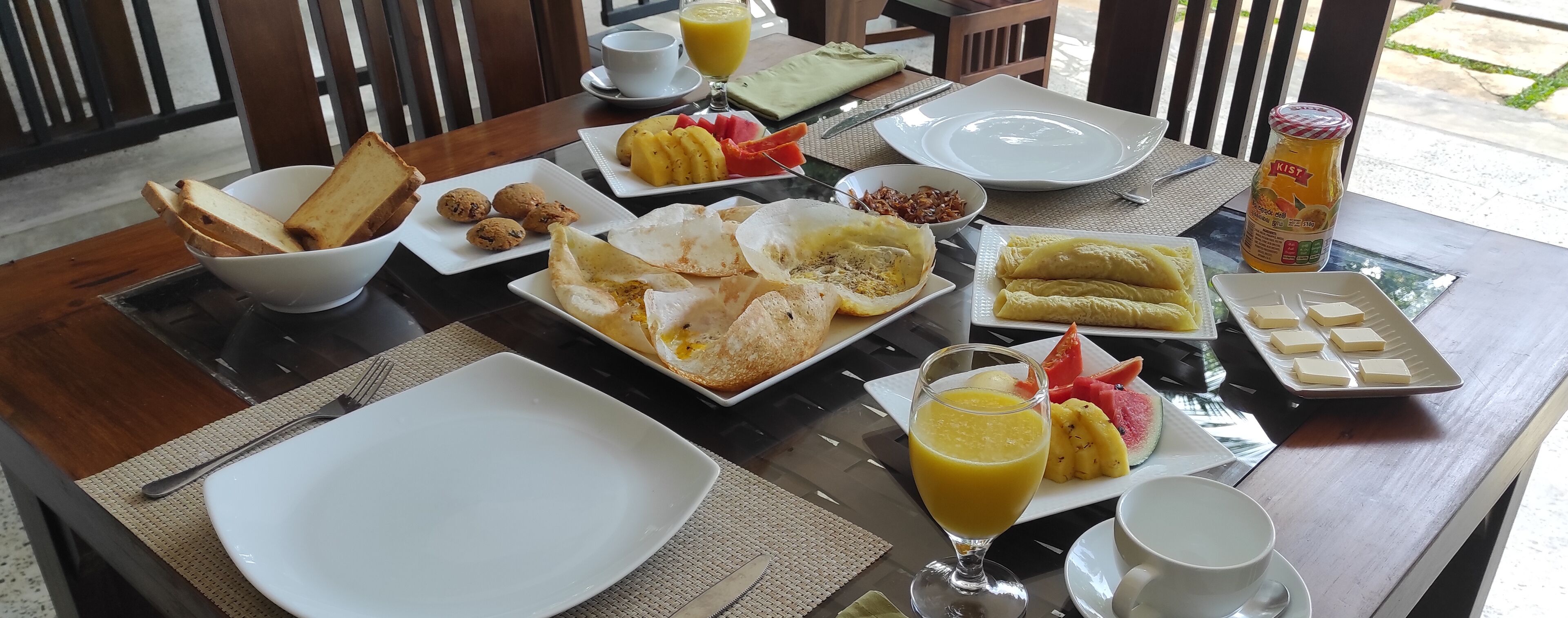 A breakfast table with various dishes including toast, eggs, and fruit.