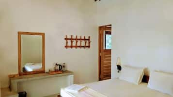 A bedroom with a bed, a bedside table, a mirror, and a wall-mounted light fixture.