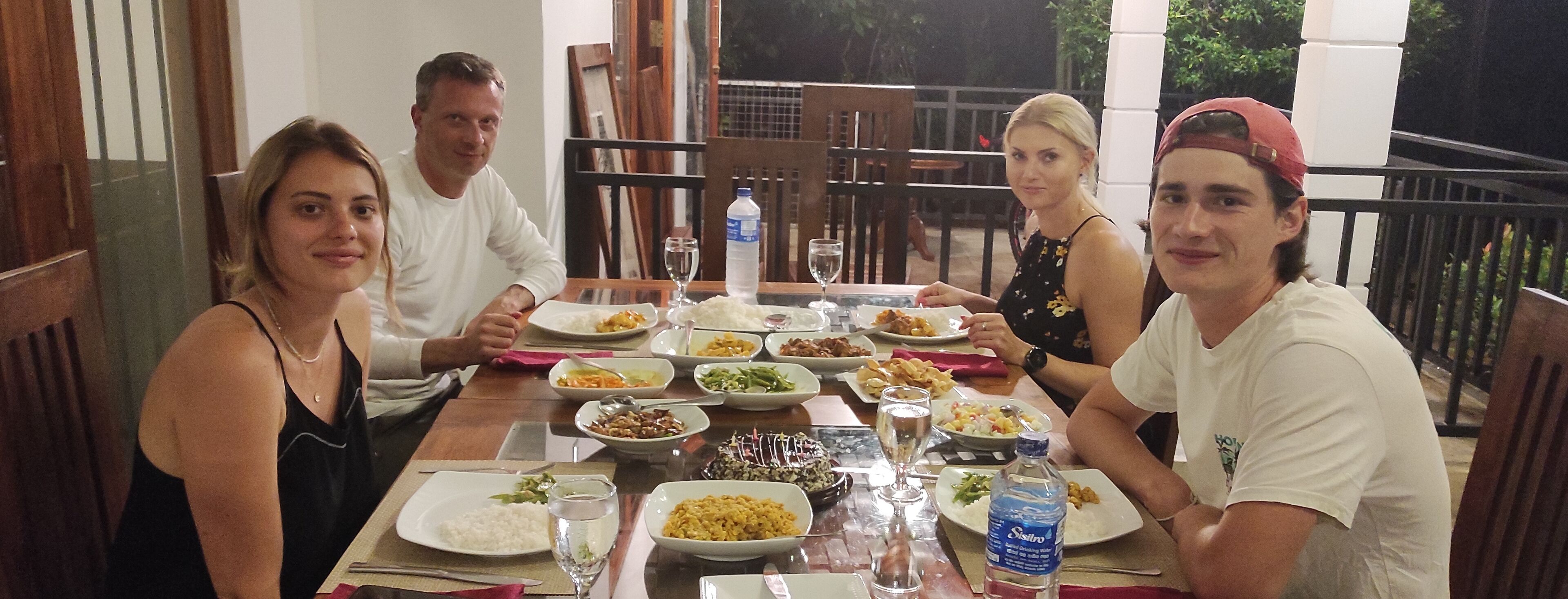 A group of people dining at a table with various dishes and drinks.