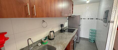 A kitchen with granite countertops, stainless steel appliances, wooden cabinets, and a tiled backsplash.