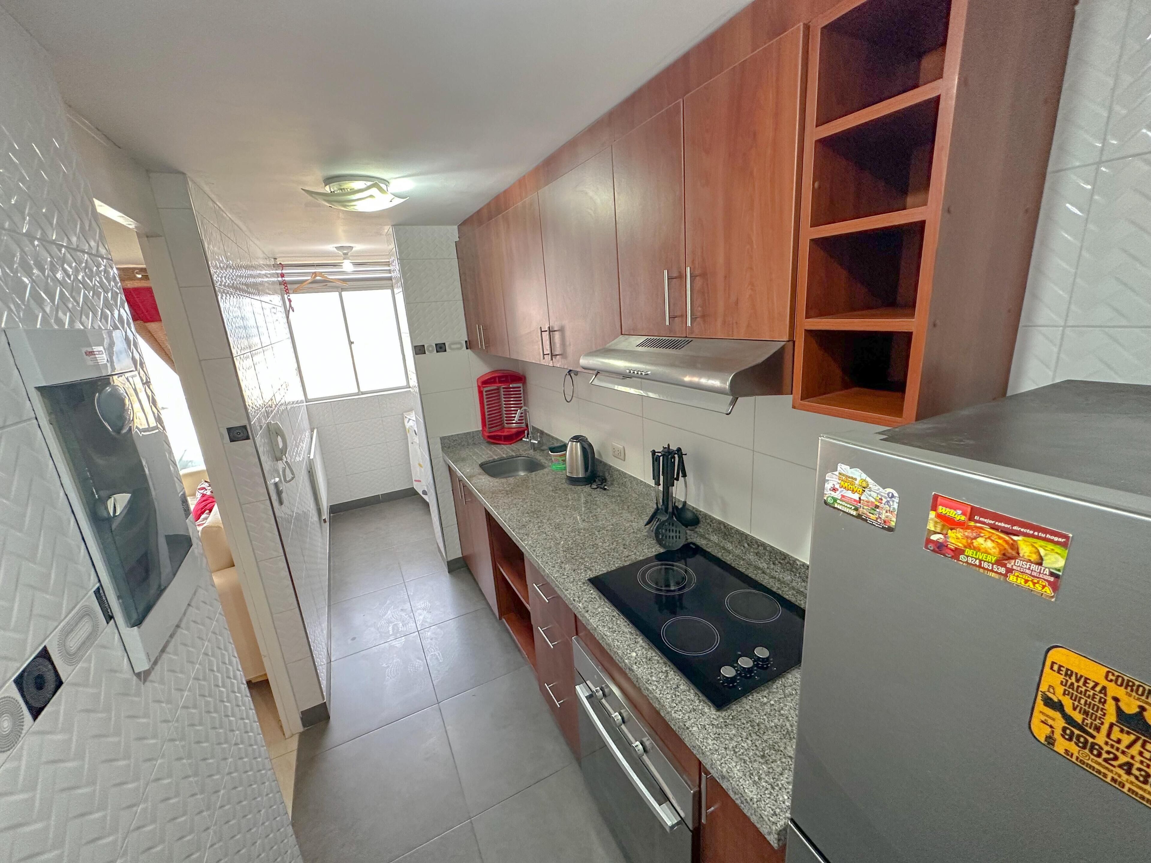 Una cocina moderna con encimeras de granito, electrodomésticos de acero inoxidable y armarios de madera.