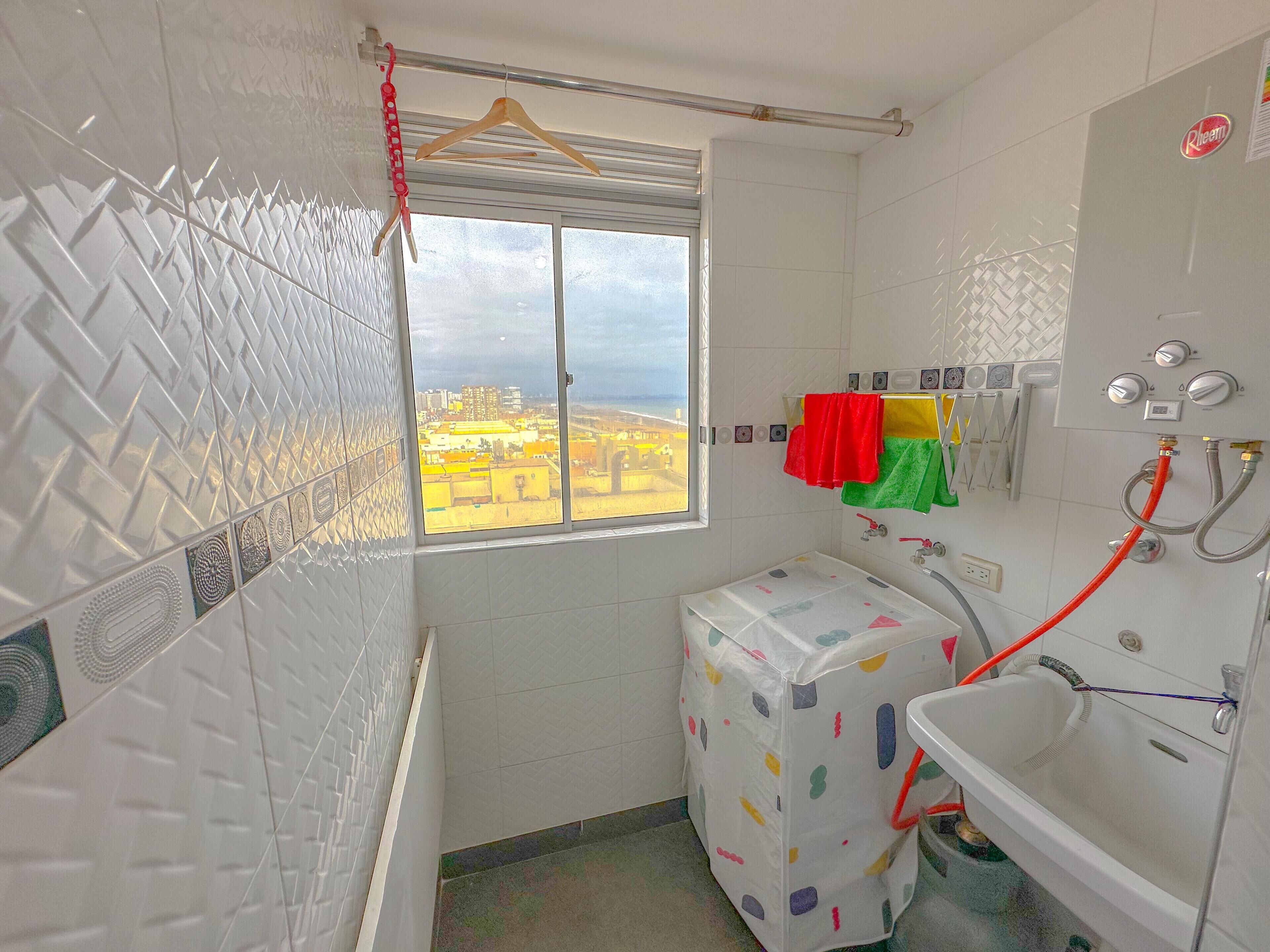 A bathroom with a window, a shower, a sink, and a toilet.