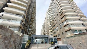 A high-rise building with multiple balconies and a glass entrance.