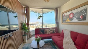 A modern living room with a red sofa, a small table, and a large window offering a city view.