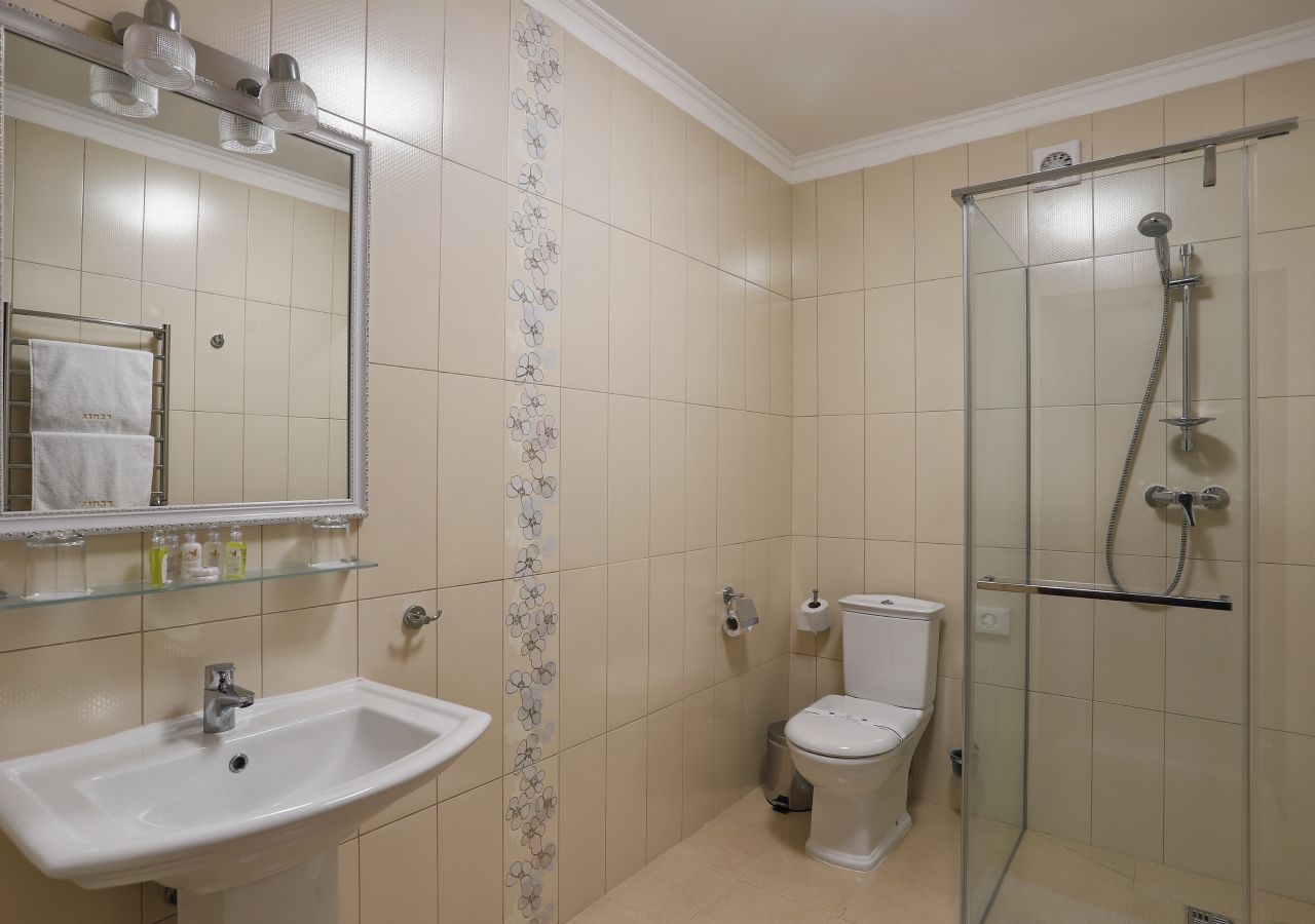 A bathroom with a sink, toilet, and glass-enclosed shower.