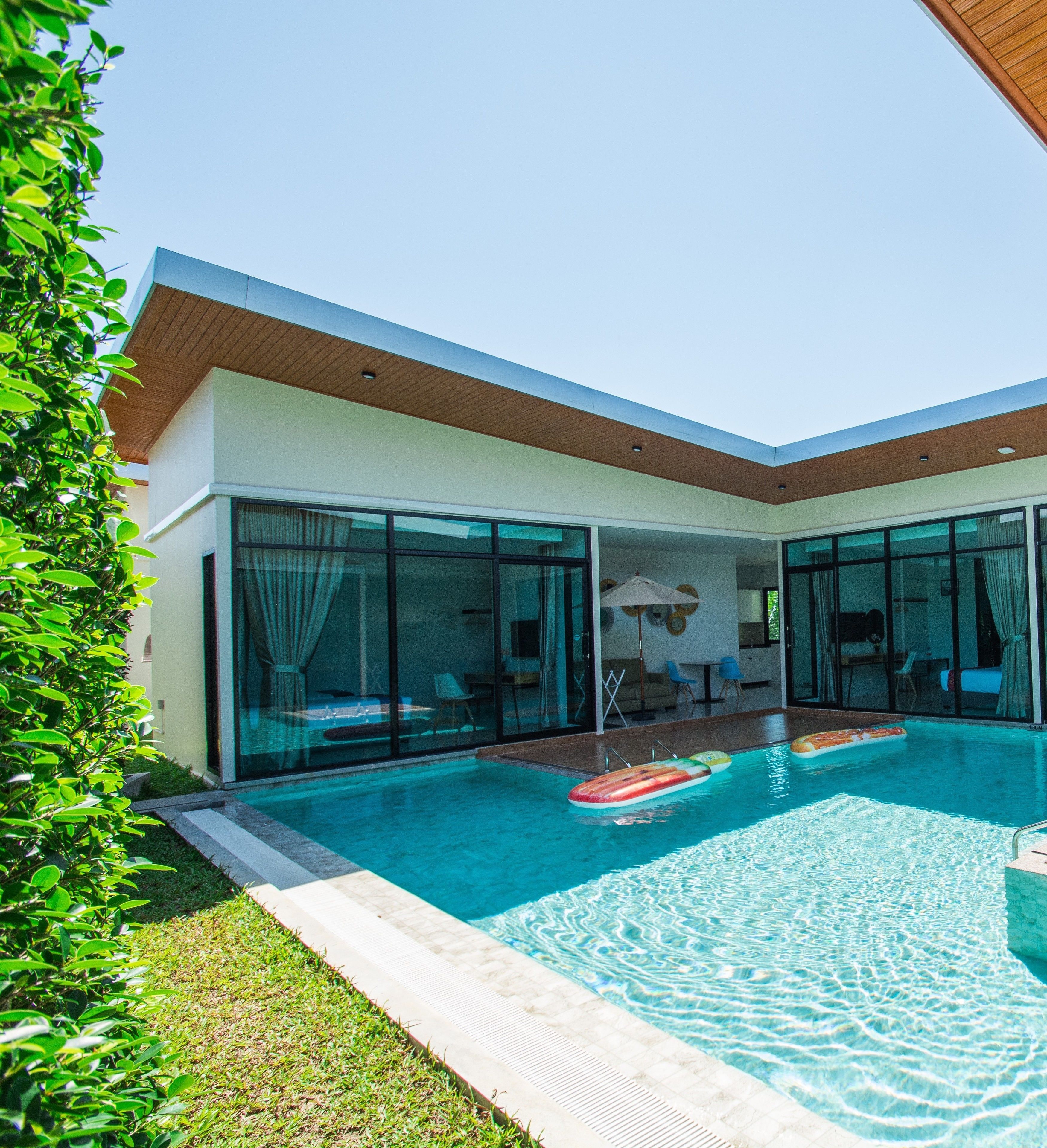 A modern house with a swimming pool, large glass doors, and a well-maintained lawn.