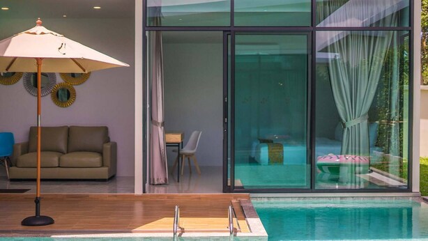 Ein moderner Innenpool mit Holzterrasse, einer Couch und einem Essbereich mit Tisch und Stühlen.
