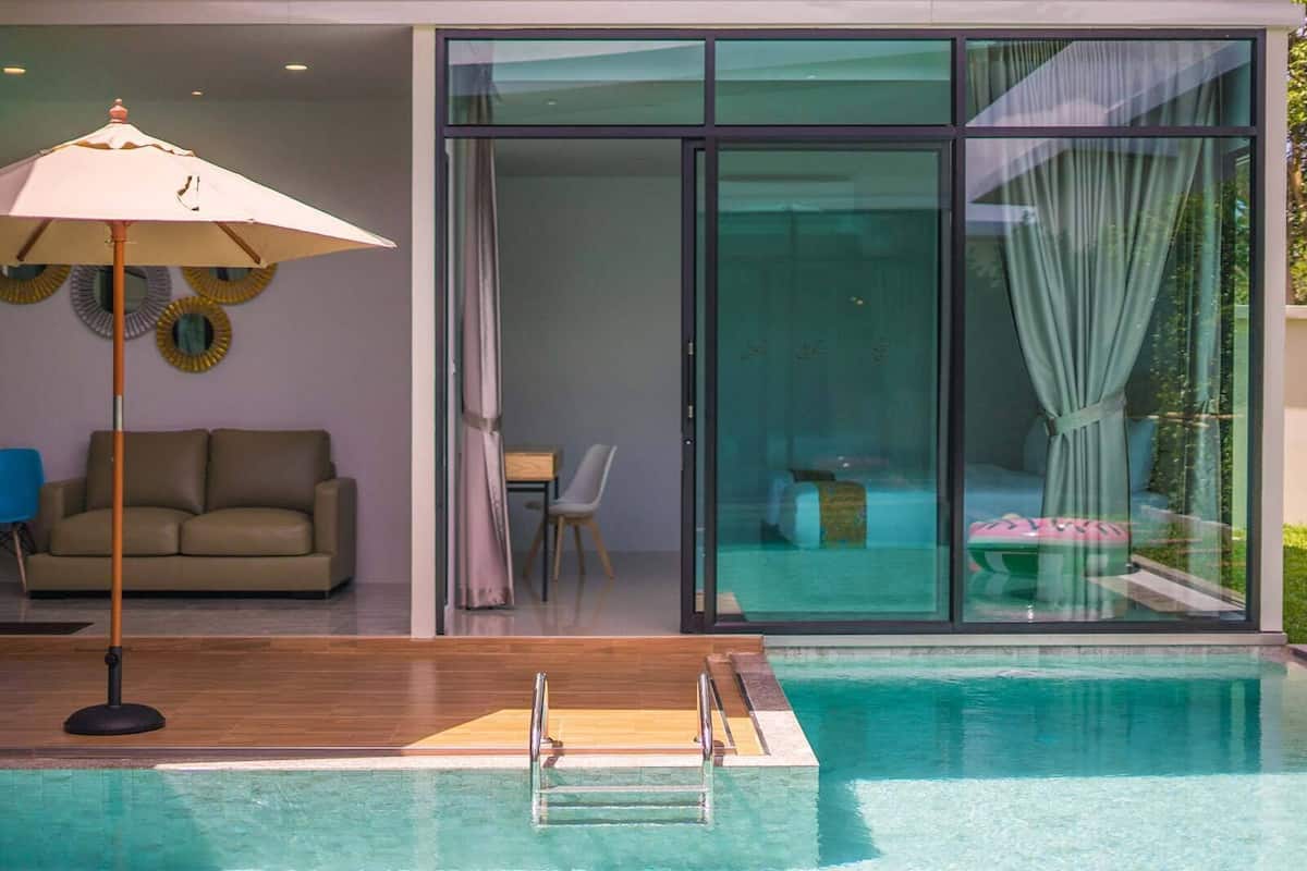 Ein moderner Innenpool mit Holzterrasse, einer Couch und einem Essbereich mit Tisch und Stühlen.