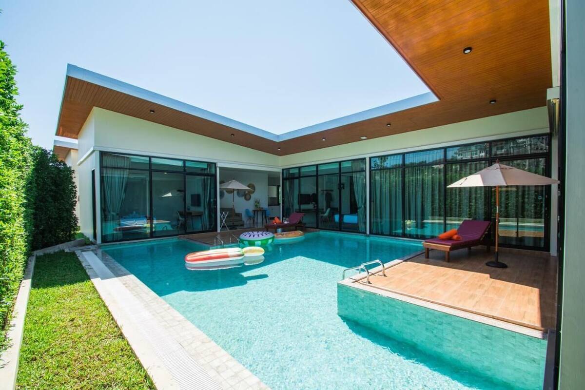 Ein modernes Haus mit Swimmingpool, Glasfenstern und einer Holzterrasse.
