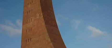 A tall brick tower with a curved base, surrounded by snow.