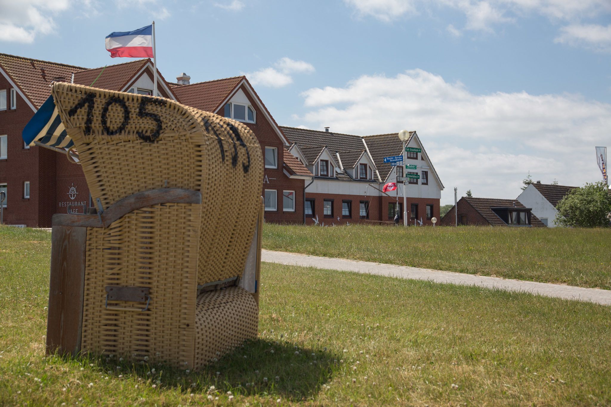 A wicker chair with the number 105, a flag, and a building in the background.