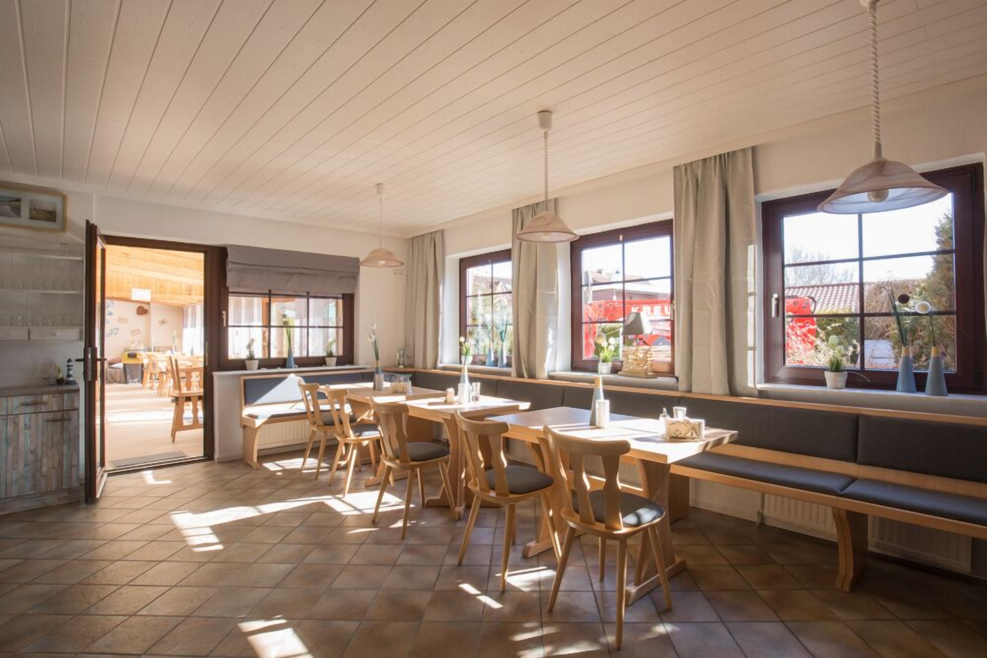 A dining area with wooden furniture, large windows, and a view of the outside.