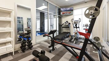 A gym with exercise equipment, a treadmill, and a mirrored wall.