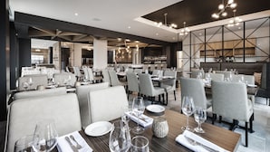 Un interior de restaurante moderno con varias mesas, sillas y una zona de bar.