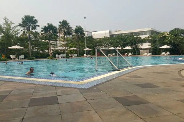 Relax by the pool surrounded by lush greenery and palm trees.