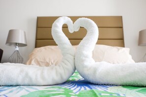 Ein Bett mit einer herzförmigen Handtuchgestaltung, einem Kopfteil und Nachttischlampen.