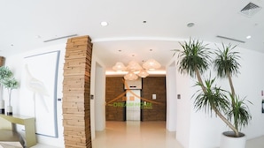 A modern lobby with a wooden accent wall, a reception desk, and a large potted plant. - Your Dream Home at Abreeza Davao (Davao)