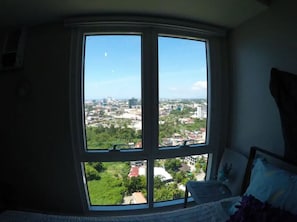 Ein Zimmer mit großem Erkerfenster und Blick auf die Stadt.